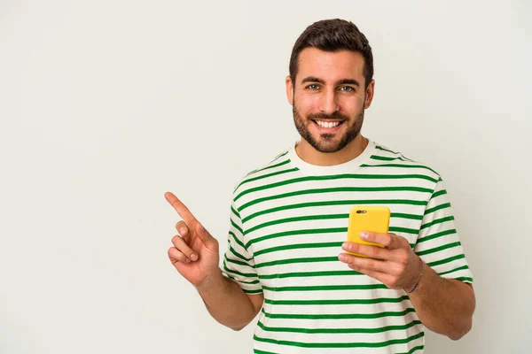 Jovem Caucasiano Segurando Telefone Celular Isolado Fundo Branco Sorrindo Apontando — Fotografia de Stock