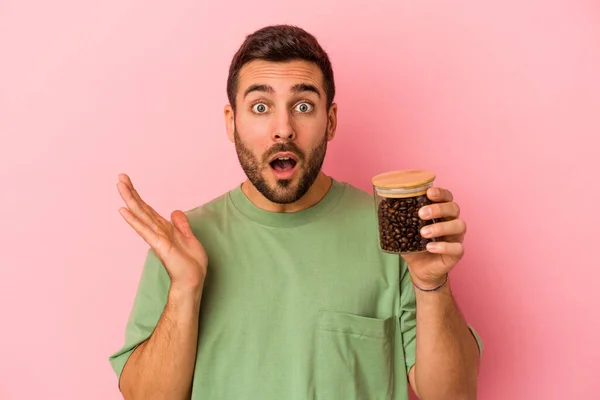 Junger Kaukasischer Mann Hält Eine Kaffeeflasche Isoliert Auf Rosa Hintergrund — Stockfoto