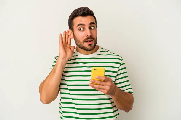 Młody Biały Człowiek Trzymając Telefon Komórkowy Odizolowany Białym Tle Próbuje — Zdjęcie stockowe