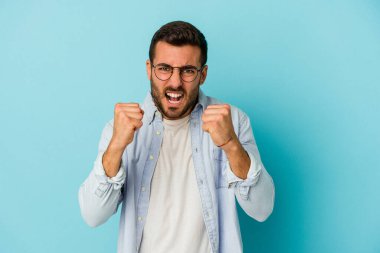 Mavi arka planda izole edilmiş genç beyaz adam gergin elleriyle çığlık atıyor..