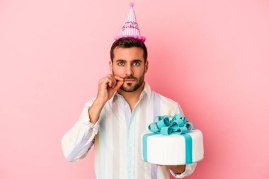 Doğumgününü kutlayan beyaz bir adam pembe arka planda izole edilmiş dudaklarında parmaklarıyla bir sır saklıyor..