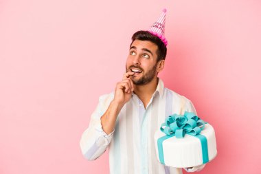 Doğumgününü kutlayan beyaz bir adam pembe arka planda izole edilmiş rahat bir şekilde fotokopi odasına bakan bir şey düşünüyor..