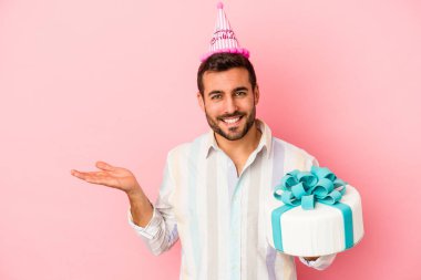 Doğumgününü kutlayan beyaz bir adam pembe arka planda izole edilmiş bir şekilde bir avuç içinde fotokopi alanı ve belinde başka bir el tutarken görülüyor..