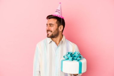 Genç beyaz adam doğum gününü pembe arka planda yalnız kutluyor. Gülümsüyor, neşeli ve keyifli..