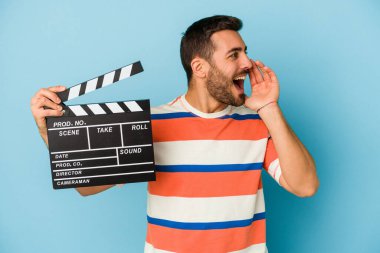 Kafkasyalı genç bir adam mavi arka planda izole edilmiş bir alçıpan tutuyor bağırıyor ve avuç içini açık tutuyordu..