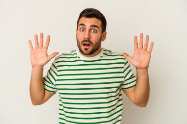 Beyaz arka planda izole edilmiş genç beyaz adam gökyüzüne haykırıyor, yukarı bakıyor, hayal kırıklığına uğramış..