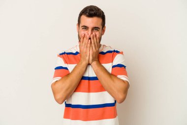 Beyaz arka planda izole olmuş genç beyaz bir adam bir şeye gülüyor, ağızlarını ellerle kapatıyor..