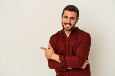 Beyaz arka planda izole edilmiş genç beyaz adam işaret parmağıyla işaret ederek gülümsüyor..