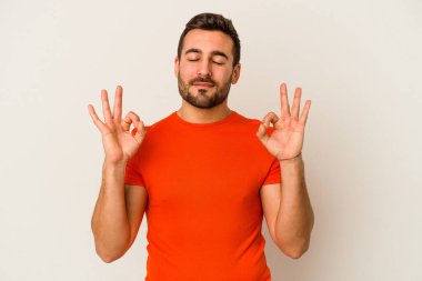 Beyaz arka planda izole edilmiş genç beyaz adam yoğun bir günün ardından rahatlıyor. Yoga yapıyor..