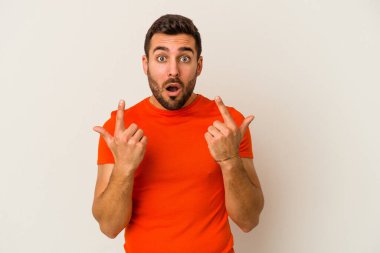 Beyaz arka planda izole edilmiş genç beyaz adam ağzı açık bir şekilde üst tarafı işaret ediyor..
