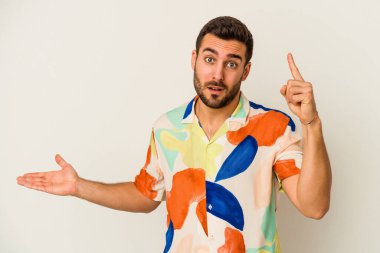 Beyaz arka planda izole edilmiş genç beyaz bir adam elinde bir ürün tutuyor ve.