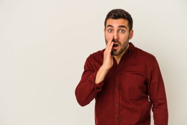 Beyaz arka planda izole edilmiş genç beyaz bir adam gizli bir sıcak fren haberi veriyor ve yana bakıyor.