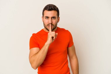 Beyaz arka planda izole edilmiş genç beyaz bir adam ya sır saklıyor ya da sessizlik istiyor..