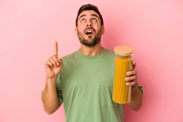 Ung Kaukasisk Man Håller Pasta Burk Isolerad Rosa Bakgrund Pekar — Stockfoto