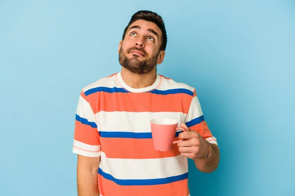 Joven Hombre Caucásico Sosteniendo Una Taza Aislada Sobre Fondo Azul —  Fotos de Stock