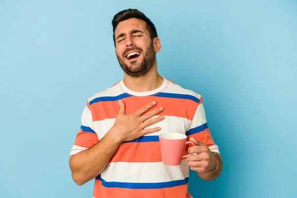 Ung Kaukasier Man Håller Mugg Isolerad Blå Bakgrund Skrattar Högt — Stockfoto