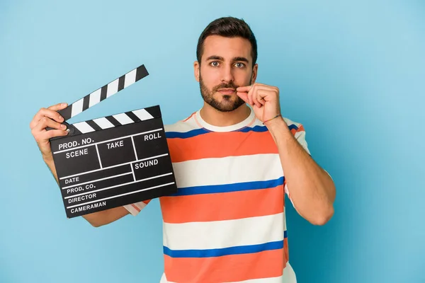 Young Caucasian Man Holding Clapperboard Isolated Blue Background Fingers Lips — Stock Photo, Image