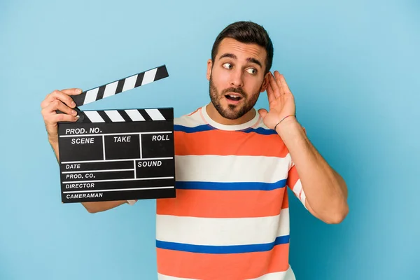 Young Caucasian Man Holding Clapperboard Isolated Blue Background Trying Listening — Stock Photo, Image