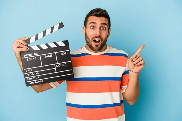 Young Caucasian Man Holding Clapperboard Isolated Blue Background Pointing Side — Stock Photo, Image