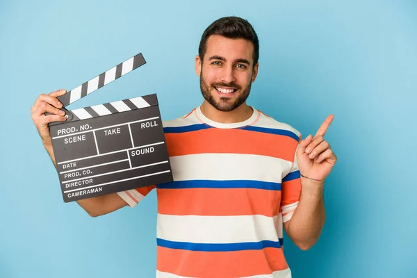 Young Caucasian Man Holding Clapperboard Isolated Blue Background Smiling Pointing — Stock Photo, Image