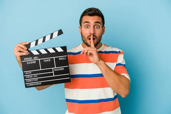 Young Caucasian Man Holding Clapperboard Isolated Blue Background Keeping Secret — Stock Photo, Image