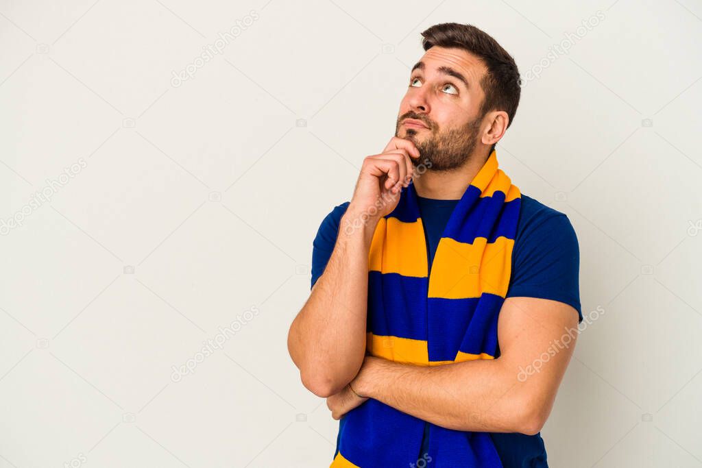 Young caucasian fan of a soccer team isolated on white background looking sideways with doubtful and skeptical expression.