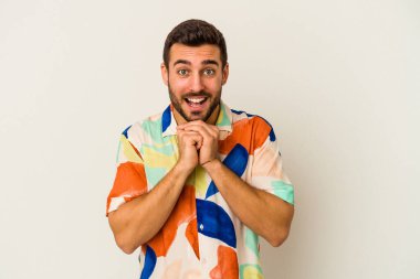 Beyaz arka planda izole genç beyaz adam ellerini çenesinin altında tutuyor, mutlu bir şekilde yana bakıyor..