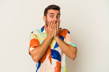 Beyaz arka planda izole edilmiş genç beyaz adam şok olmuş, ağzı ellerle kaplanmış, yeni bir şey keşfetmeye hevesli..