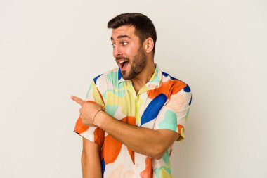 Beyaz arka planda izole edilmiş genç beyaz adam gülümseyen, neşeli ve keyifli bir tarafa bakıyor..