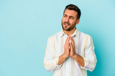 Kafkasyalı genç bir adam mavi arka planda izole edildi. Aklında bir plan kuruyor, bir fikir kuruyor..