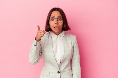 Pembe arka planda izole edilmiş yeşil takım elbiseli genç melez bir kadının bir fikri, ilham verici bir fikri var..