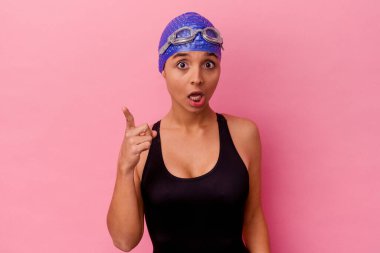 Genç yüzücü melez kadın pembe arka planda izole edilmiş bir fikri var, ilham verici bir kavram..