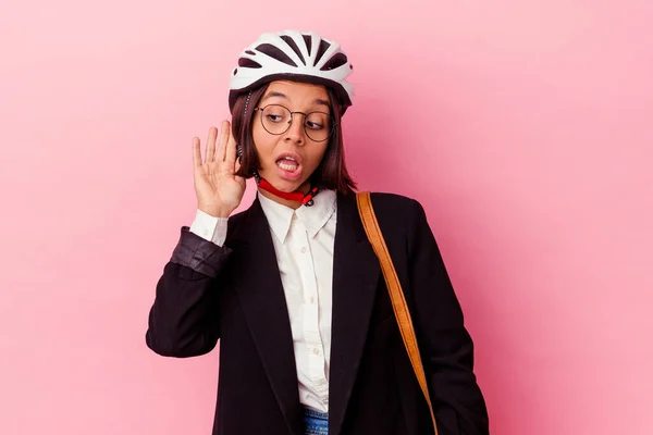若いビジネス混合レースの女性はピンクの背景に隔離された自転車のヘルメットを身に着けているゴシップを聞こうと — ストック写真