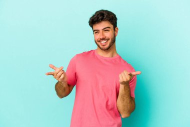 Kafkasyalı genç adam mavi arka planda izole edilmiş neşeli bir şekilde gülüyor. Mutluluk kavramı.