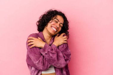 Genç kıvırcık Latin kadın pembe arka planda izole edilmiş, güler yüzlü ve mutlu..