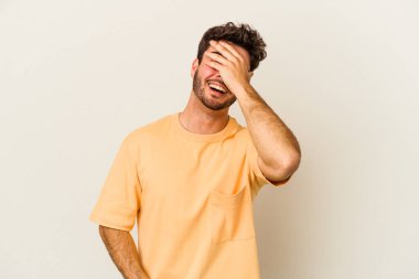 Beyaz arka planda izole olmuş genç beyaz bir adam ellerini başının üstünde tutarak neşeyle gülüyor. Mutluluk kavramı.