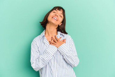 Mavi üzerine izole edilmiş genç melez kadın, dost canlısı bir ifadeye sahip, avuçlarını göğsüne bastırıyor. Aşk konsepti.