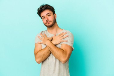 Kafkasyalı genç adam mavi arka planda izole edilmiş, güler yüzlü ve mutlu..