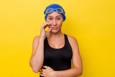 Genç Avustralyalı yüzücü kadın sarı arka planda izole edilmiş parmakları dudaklarında bir sır saklıyor..