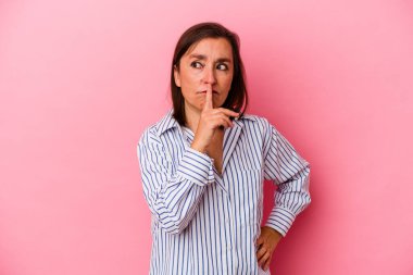 Pembe arka planda izole edilmiş orta yaşlı beyaz kadın bir sır saklıyor ya da sessizlik istiyor..