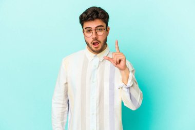 Kafkasyalı genç bir adam mavi arka planda izole edilmiş. Bir fikri, ilham verici bir fikri var..