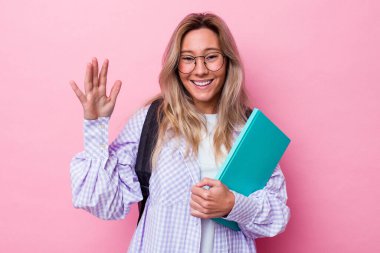 Genç Avustralyalı bir öğrenci pembe arka planda izole edilmiş. Hoş bir sürpriz, heyecanlı ve el kaldırıyor..
