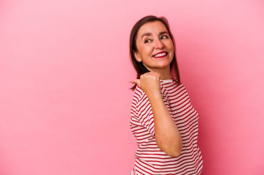 Orta yaşlı beyaz kadın pembe arka plan noktalarında izole edilmiş, başparmak uzakta, gülüyor ve kaygısız..
