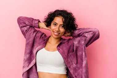 Genç kıvırcık Latin kadın pembe arka planda izole kollarını uzatarak, rahat bir konumda..