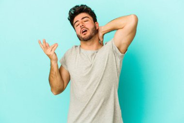 Mavi arka planda izole edilmiş genç beyaz adam öfkeyle bağırıyor..