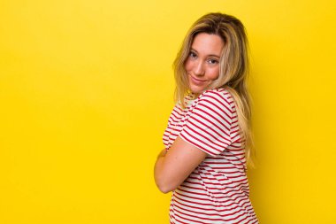 Avustralyalı genç bir kadın kendini soyutlamış kollarını kavuşturarak gülümsüyor..