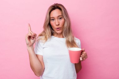 Pembe arka planda izole edilmiş pembe kupa tutan genç Avustralyalı kadın harika bir fikre sahip, yaratıcılık kavramı..