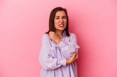 Orta yaşlı beyaz kadın pembe arka planda izole edilmiş dirsek masajı yapıyor, kötü bir hareketin ardından acı çekiyor..