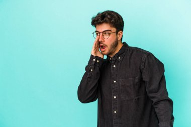 Mavi arka planda izole edilmiş genç beyaz bir adam gizli bir sıcak fren haberi veriyor ve yana bakıyor.