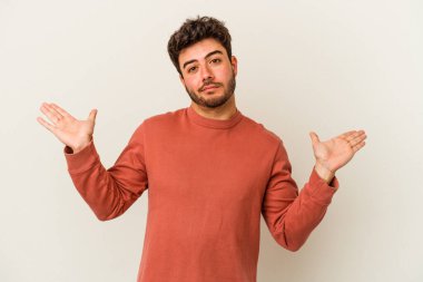 Beyaz arka planda izole edilmiş genç beyaz bir adam sorgulama sırasında omuz silkiyor ve şüphe duyuyor..